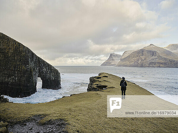 Frau beim Spaziergang in der Nähe von Drangarnir auf den Färöer Inseln