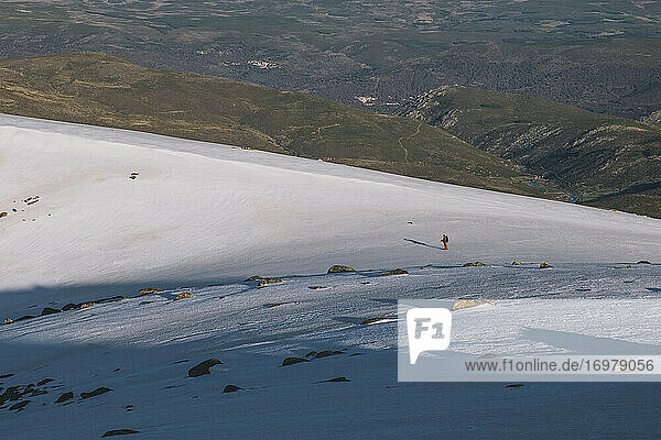Junger Mann in der Ferne beim Abstieg auf einem verschneiten Bergstück  Gredos  Spanien