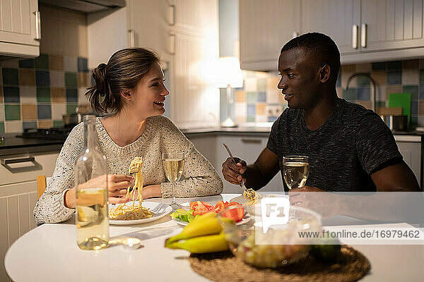 Multiethnisches Paar  das abends zu Hause Nudeln isst