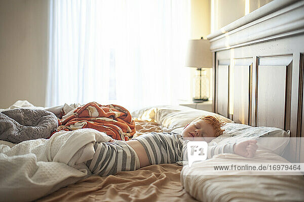 Kleinkind Junge 3-4 Jahre alt schlafend in unordentlichen Eltern Bett in ziemlich Licht
