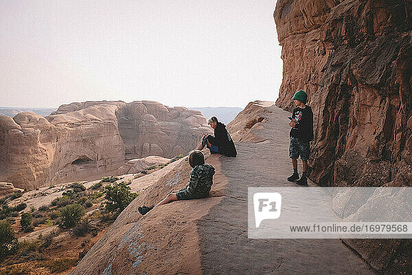 Drei Jungen  die während einer Wanderung in der Wüste ihre Handys überprüfen.
