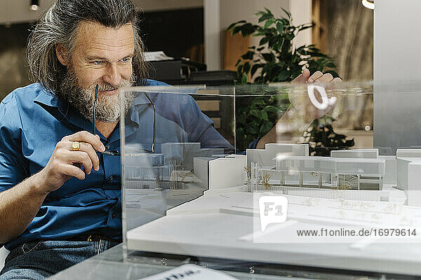 Reifer Mann mit Bart  der ein Modell einer Konstruktion betrachtet. Architektur Konzept