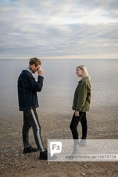 Mann fotografiert seine Freundin am Seeufer