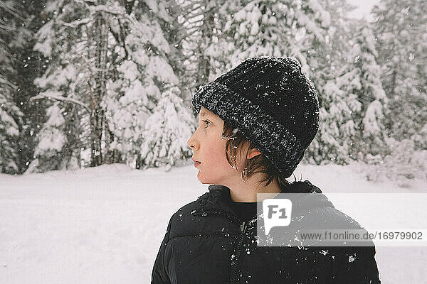 Young Boy Stands in profile with Snowflakes Sticking to his Beanie.