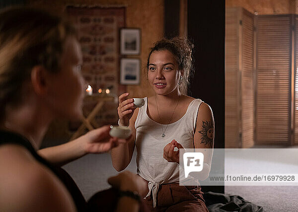 Frau mit Tee im Gespräch mit einer Freundin im Yogastudio