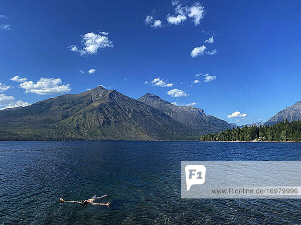 A man floats on his back in McDonald Lake in Glacier National Park  MT