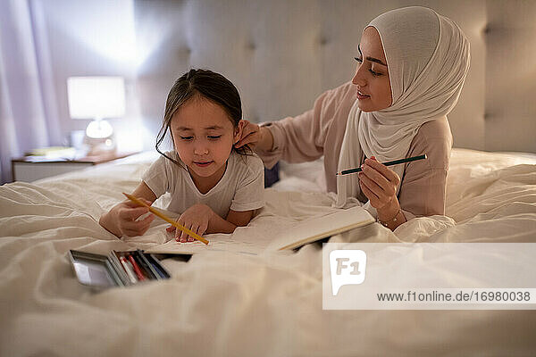 Muslimische Mutter kümmert sich um ihre zeichnende Tochter