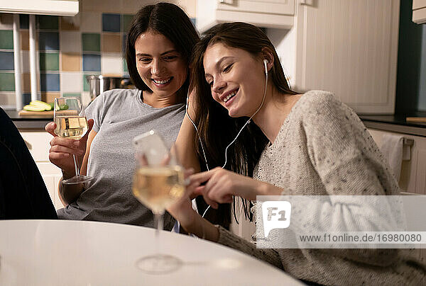 Fröhliche Frauen blättern durch die Wiedergabeliste  während sie auf einer Party Musik hören