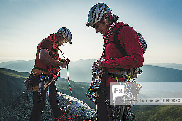 Mann und Frau sortieren Kletterausrüstung am frühen Morgen in den Bergen