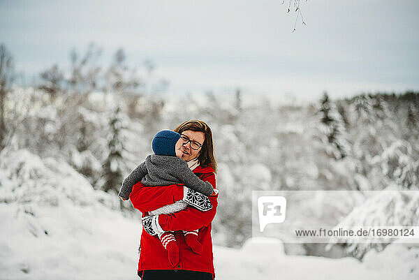 Grandmother holding grandchild baby outside in snow in winter Norway