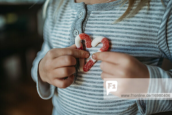 Cropped hands of girl holding candy canes in a heart on her chest