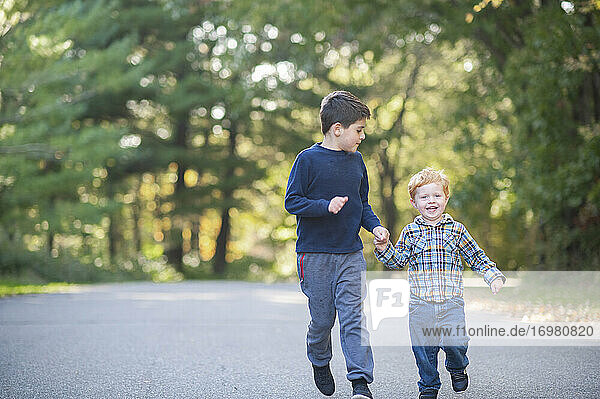 Two brothers running down a road while hands smiling