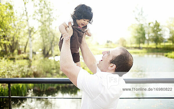 Vater hält seine Tochter auf einer Parkbrücke in die Luft