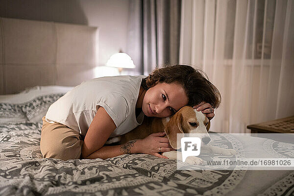 Junge Frau  die ihren Hund auf dem Bett umarmt