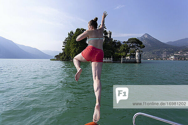 Eine kaukasische Frau springt von einem Boot in einen See in Italien