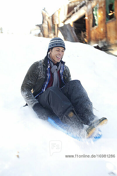 Man sliding down snowy hill in sled