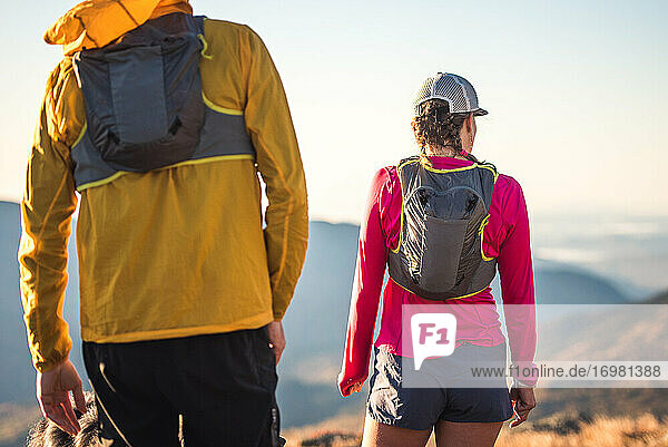 Mann und Frau  die als Trailrunner stehen und auf die Berge schauen