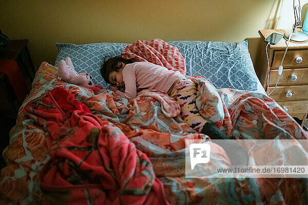 Junges Kind gemischter Rasse Mädchen schlafen im Bett mit rosa Bettdecke