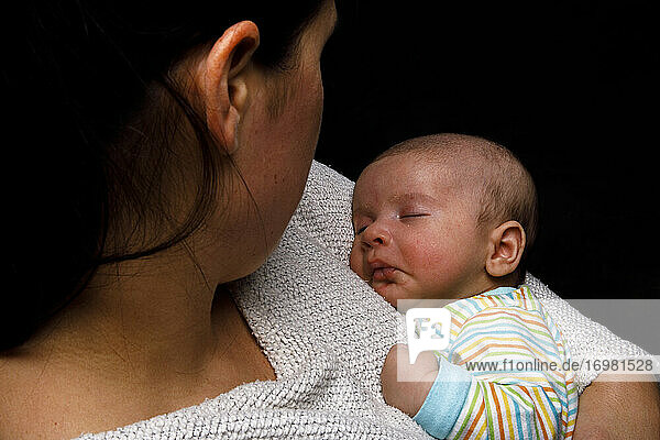 Frau hält neugeborenes Kind  das sich an die Mutter kuschelt und friedlich schläft