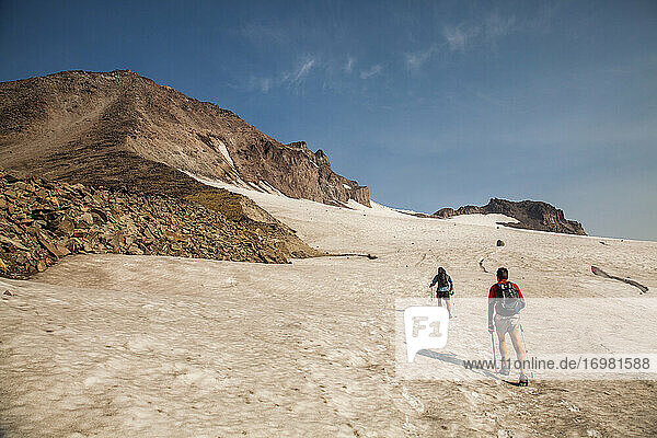 Zwei Wanderer klettern in der Morgendämmerung auf den Gipfel des Glacier Peak.