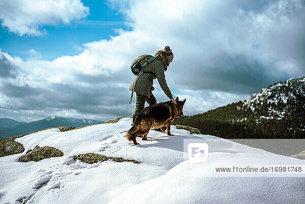 Junges Mädchen führt einen Hund durch den Schnee in den Bergen im Winter