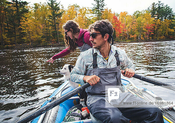 Mann und Frau beim Angeln mit Hund in einem Boot während der Laubzeit