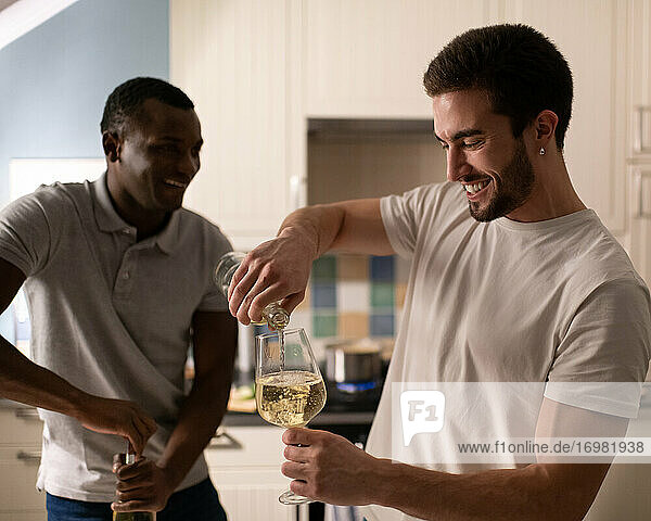 Verschiedene männliche Freunde bereiten Wein für eine Party zu Hause vor