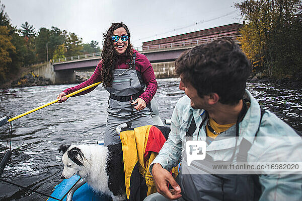 Frau lächelt Mann beim Angeln im Boot unterhalb eines Staudamms auf einem Fluss an