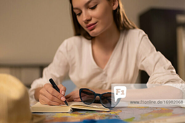 Frau schreibt während der Reiseplanung in ein Notizbuch