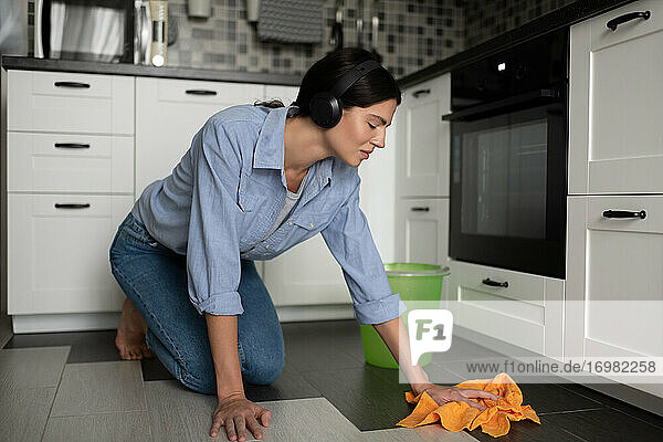 Frau,  die ihr Haus putzt und mit Kopfhörern Musik hört