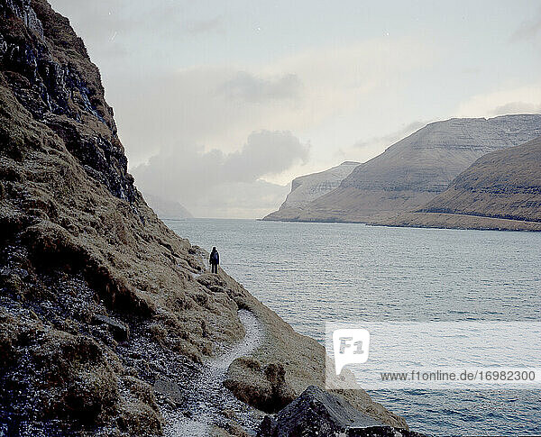 Female hiker walking along cliff in the Faroe Islands
