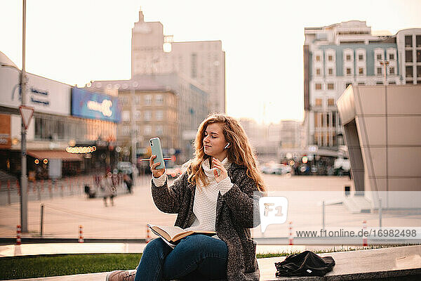 Happy teenage student girl doing video call using smart phone