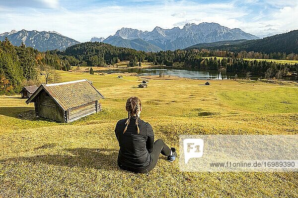 Young woman sitting in the meadow  Heustadl in a meadow at the Geroldsee  Gerold  view of Karwendel mountains  Bavaria  Germany  Europe