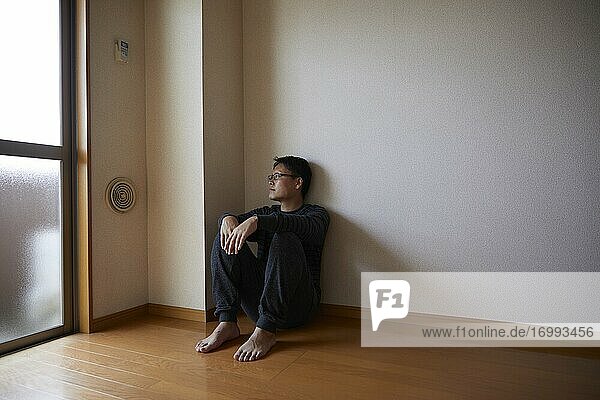 Sad Japanese man in empty apartment