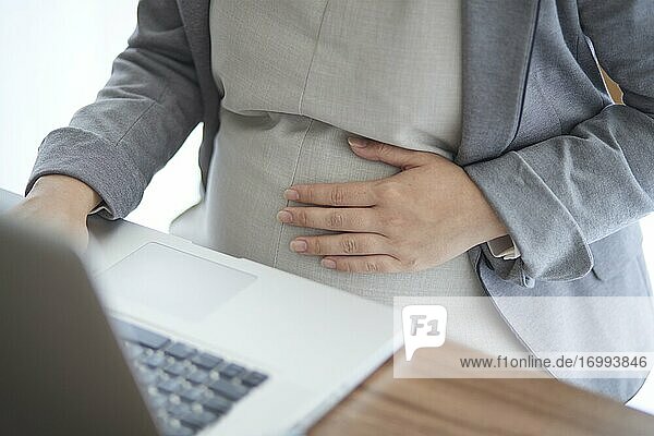 Schwangere Japanerin bei der Arbeit mit Laptop