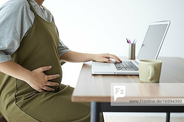 Schwangere Japanerin bei der Arbeit mit Laptop