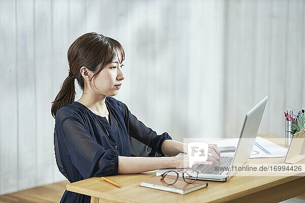 Junge japanische Geschäftsfrau arbeitet an ihrem Laptop