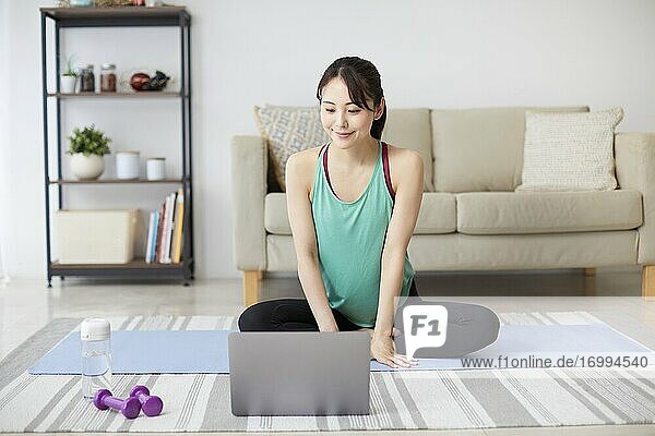Gesunde japanische Frau trainiert zu Hause