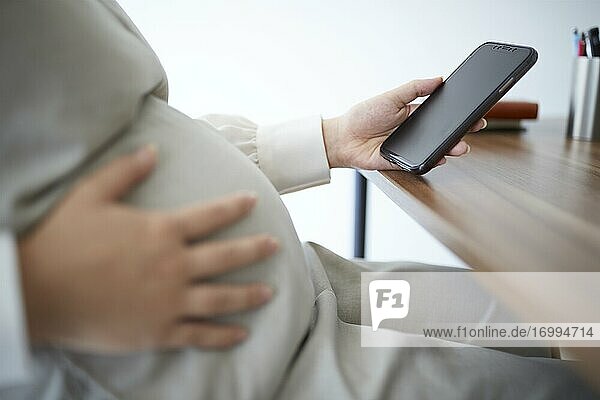 Schwangere Japanerin mit Smartphone