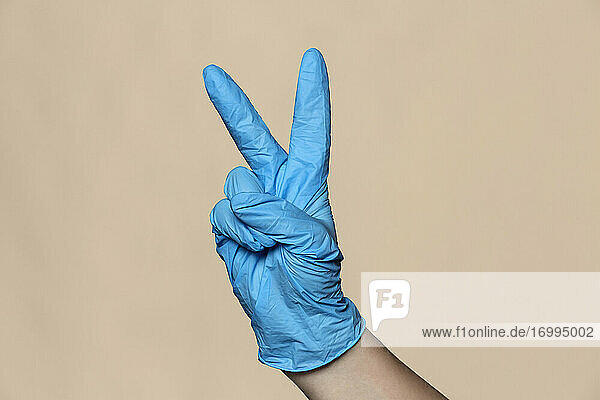 Hand im Schutzhandschuh gestikuliert Friedenszeichen