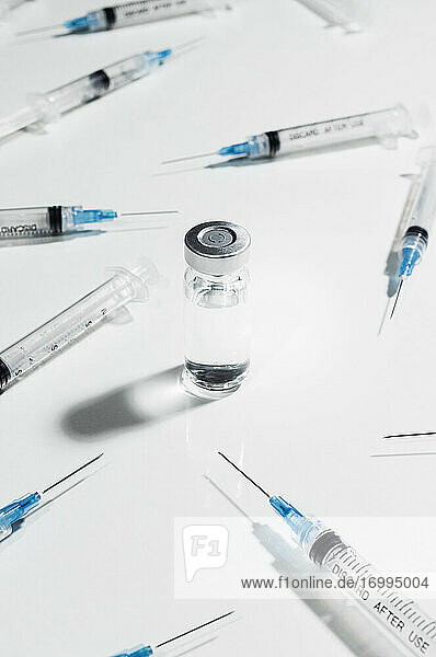 Spritzen  die die COVID-19-Impfstoffampulle umgeben  auf weißem Hintergrund