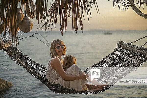 Porträt Mutter und Tochter in der Hängematte genießen Meer Sonnenuntergang