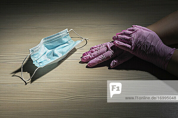 Handschuhe an den Händen neben Einwegschutzmaske
