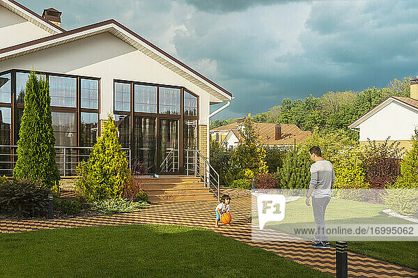 Vater und Kleinkind Sohn spielen mit Basketball in sonnigen Hinterhof