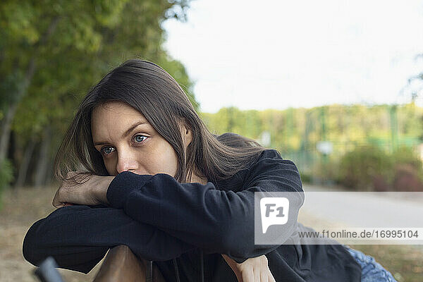 Thoughtful young brunette woman on park bench
