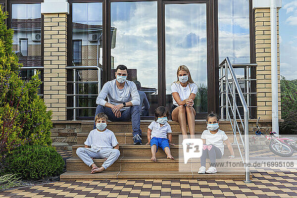 Porträt Familie in Gesichtsmasken auf Patio Schritte des Hauses