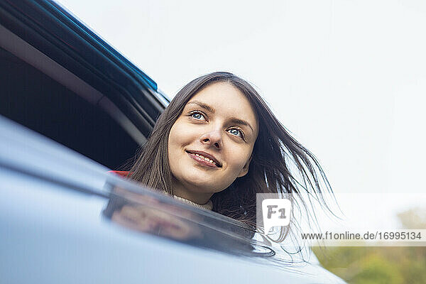 Porträt glückliche  unbekümmerte junge Frau lehnt sich aus dem Autofenster