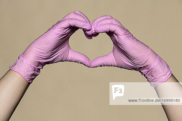 Hände in rosa Schutzhandschuhen bilden eine Herzform
