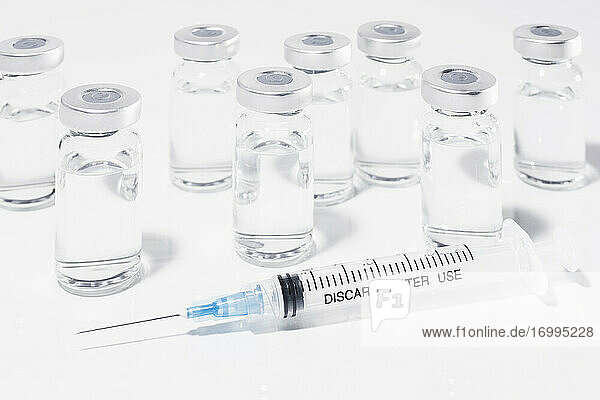 COVID-19-Impfstoff-Ampullen und Spritze auf weißem Hintergrund