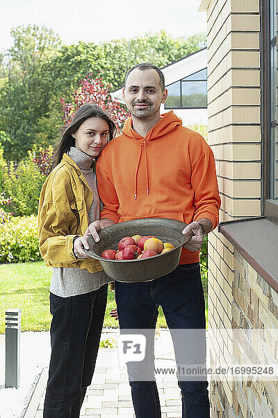 Porträt glückliches junges Paar mit Schale von frisch geernteten Äpfeln